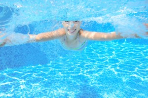 Kid swims in pool underwater, girl swimming and having fun